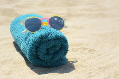 Photo of Towel with stylish sunglasses on sand outdoors, closeup and space for text. Beach accessories