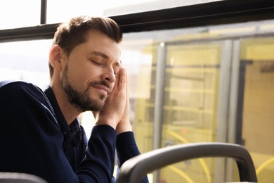 Tired man sleeping while sitting in public transport