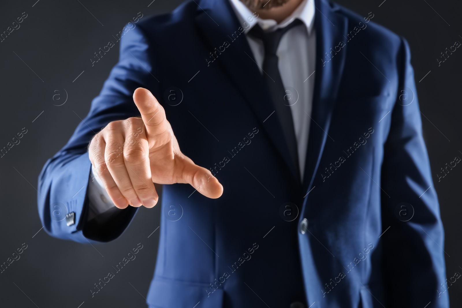 Photo of Businessman touching empty virtual screen against dark background, focus on hand