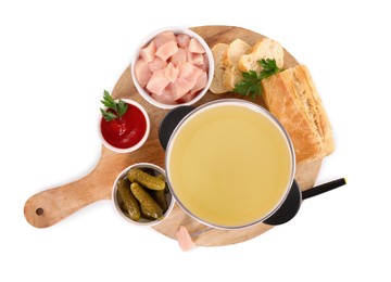 Photo of Oil in fondue pot, fork, pieces of raw meat and other products isolated on white, top view