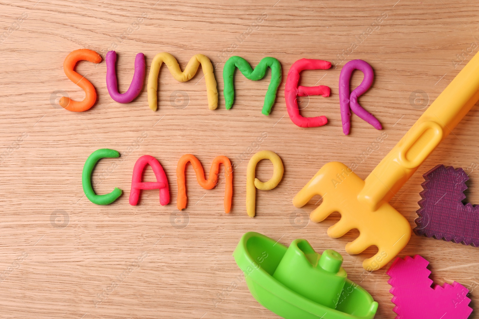 Photo of Text SUMMER CAMP made with play dough on wooden background, top view