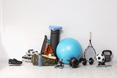 Many different sports equipment near wall indoors