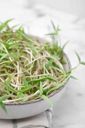 Photo of Mung bean sprouts in bowl on white marble table, closeup