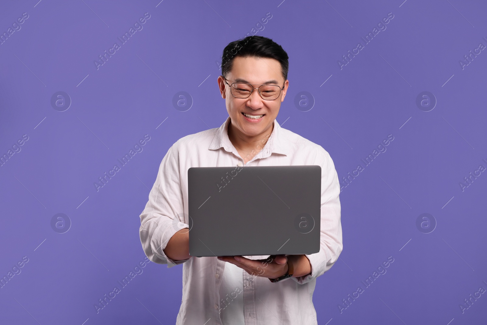 Photo of Happy man with laptop on lilac background