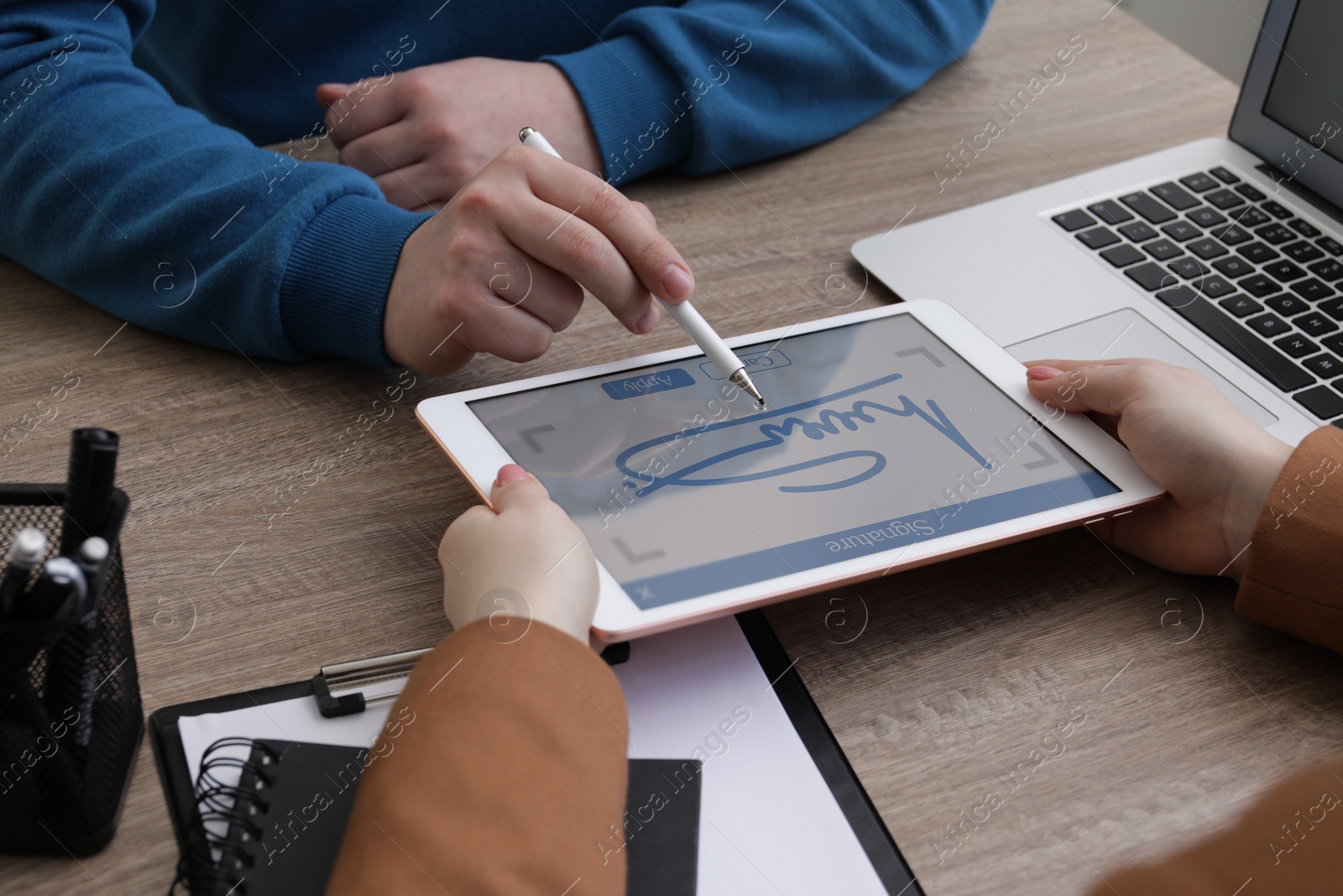 Image of Electronic signature. Man using stylus and tablet at wooden table, closeup