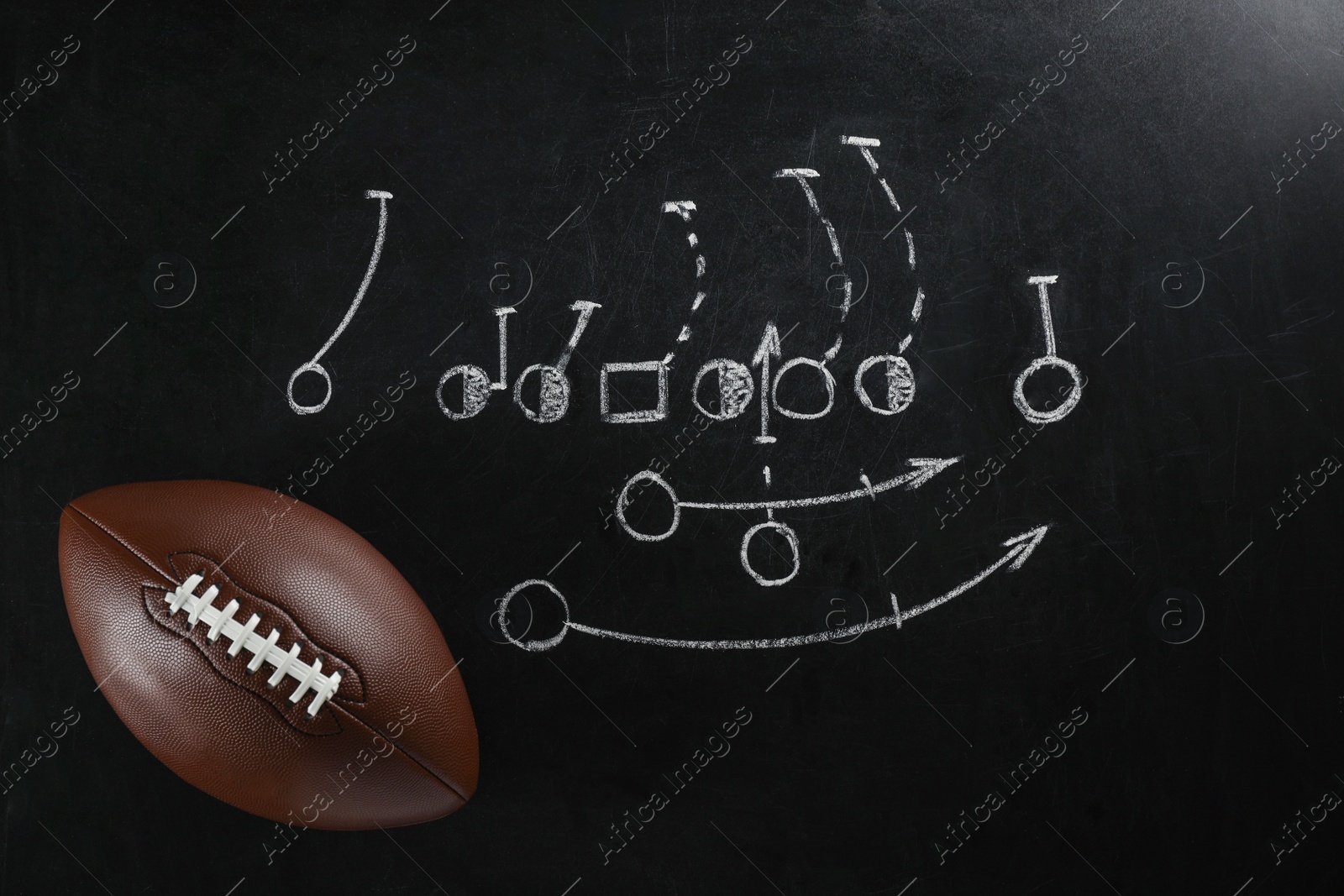 Photo of Leather American football on chalkboard with scheme of game, top view