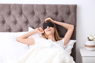 Photo of Young beautiful woman with sleeping mask waking up in morning at home
