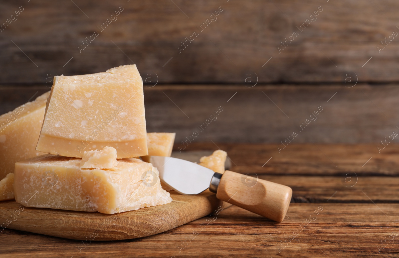 Photo of Delicious parmesan cheese with knife on wooden table, closeup. Space for text