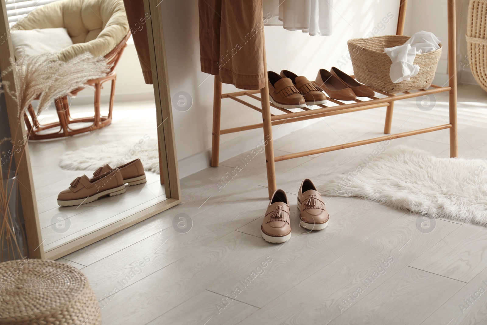 Photo of Rack with stylish shoes and women's clothes in dressing room. Modern interior design