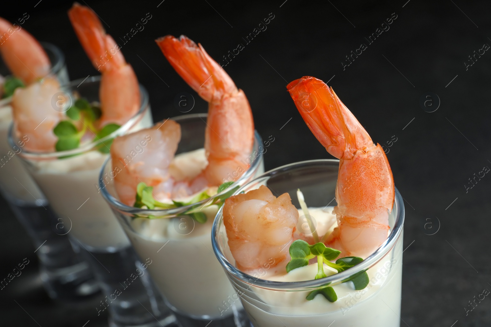 Photo of Glasses with boiled shrimps and sauce on dark background