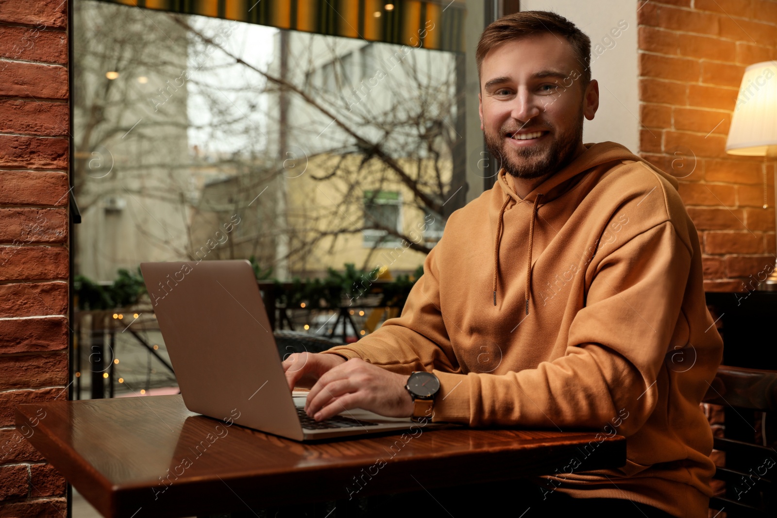 Photo of Male blogger working with laptop at table in cafe