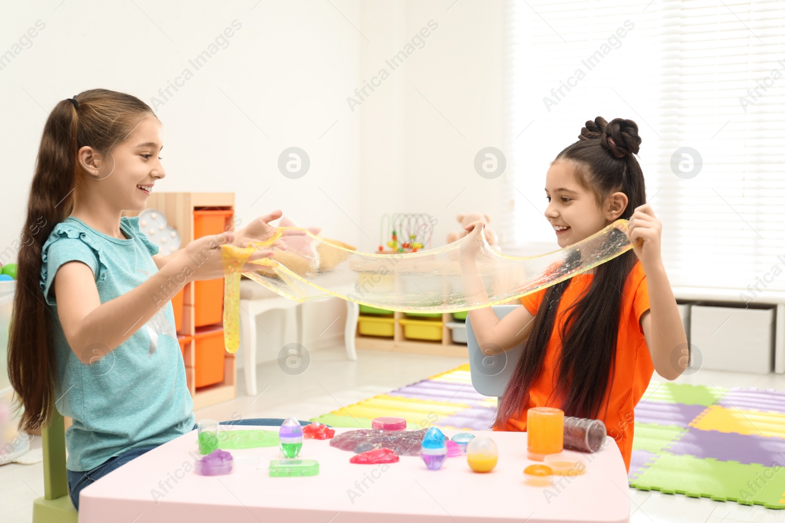 Photo of Happy girls playing with slime in room