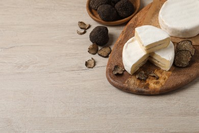 Delicious cheese and fresh black truffles on white wooden table. Space for text