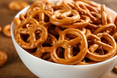 Photo of Delicious pretzel crackers in bowl on wooden table, closeup