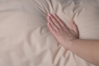 Photo of Woman touching soft beige pillow, closeup view