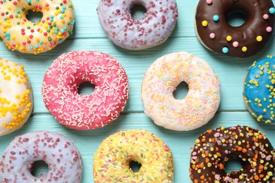 Photo of Delicious glazed donuts on blue wooden table, flat lay