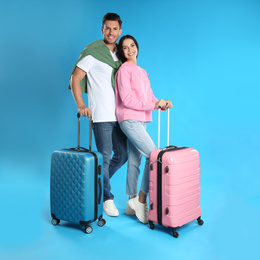 Happy couple with suitcases for summer trip on blue background. Vacation travel
