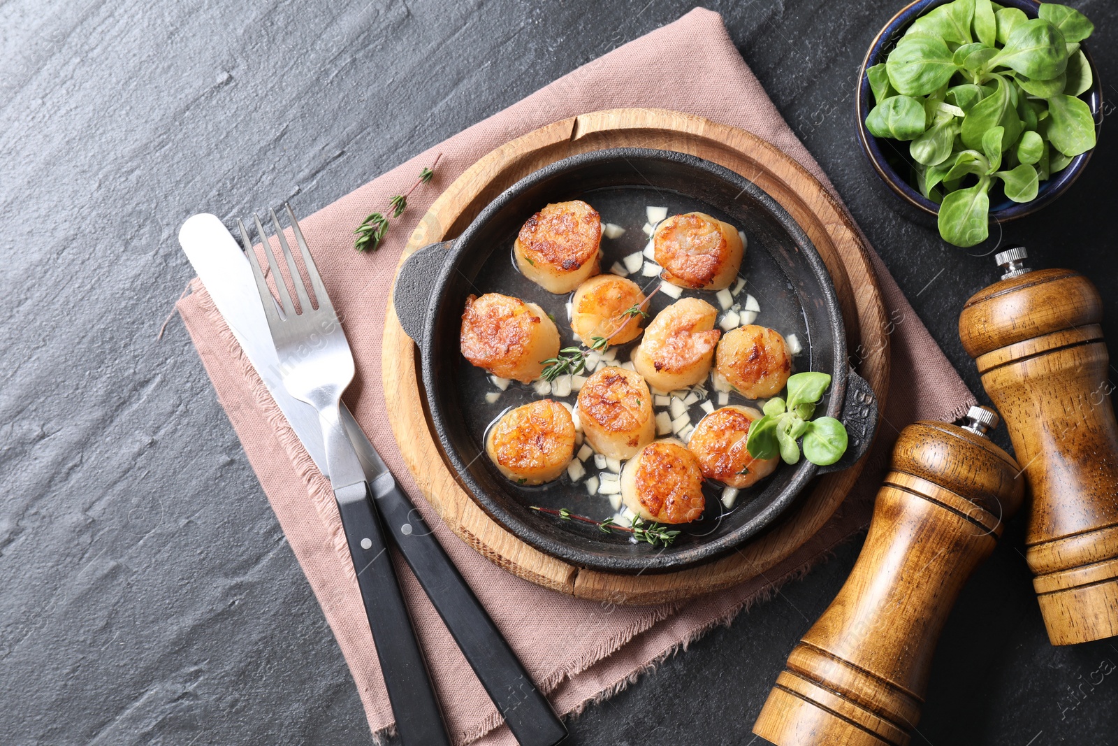 Photo of Delicious fried scallops in dish served on dark gray textured table, flat lay