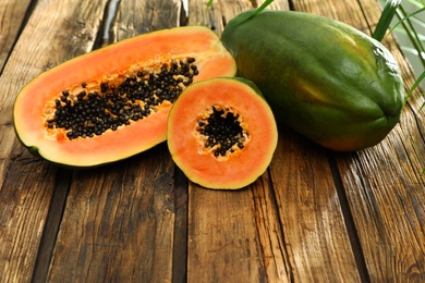 Fresh juicy ripe papayas on wooden table, space for text