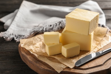 Photo of Wooden board with fresh butter and knife on table