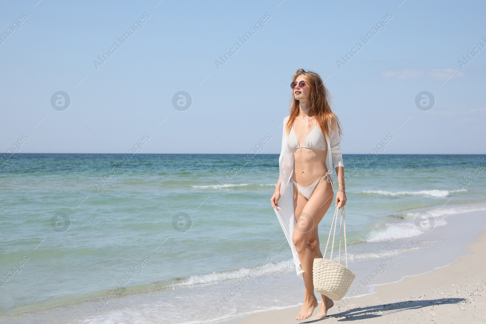 Photo of Beautiful woman with beach bag walking near sea