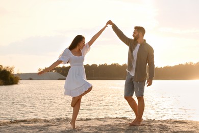 Photo of Happy couple dancing near river on sunny day