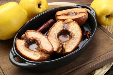 Tasty baked quinces with spices and honey in dish on table