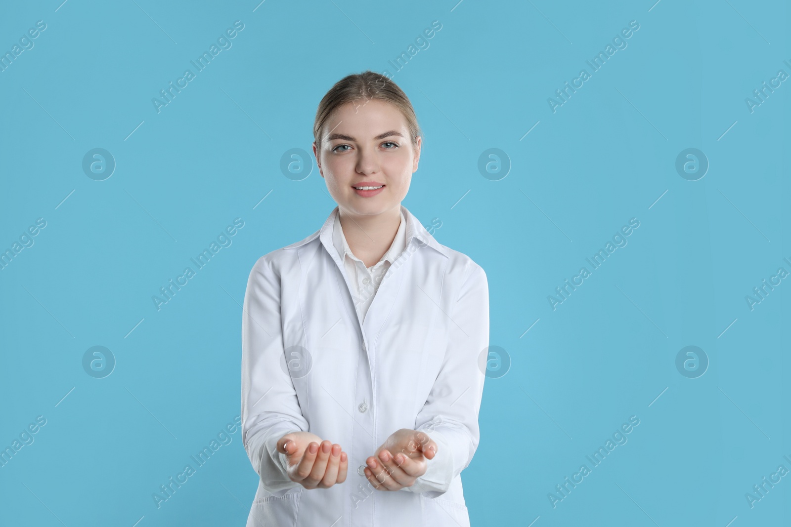 Photo of Dental assistant holding something on light blue background