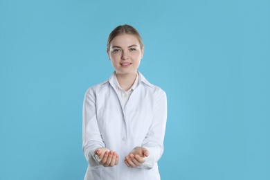 Photo of Dental assistant holding something on light blue background