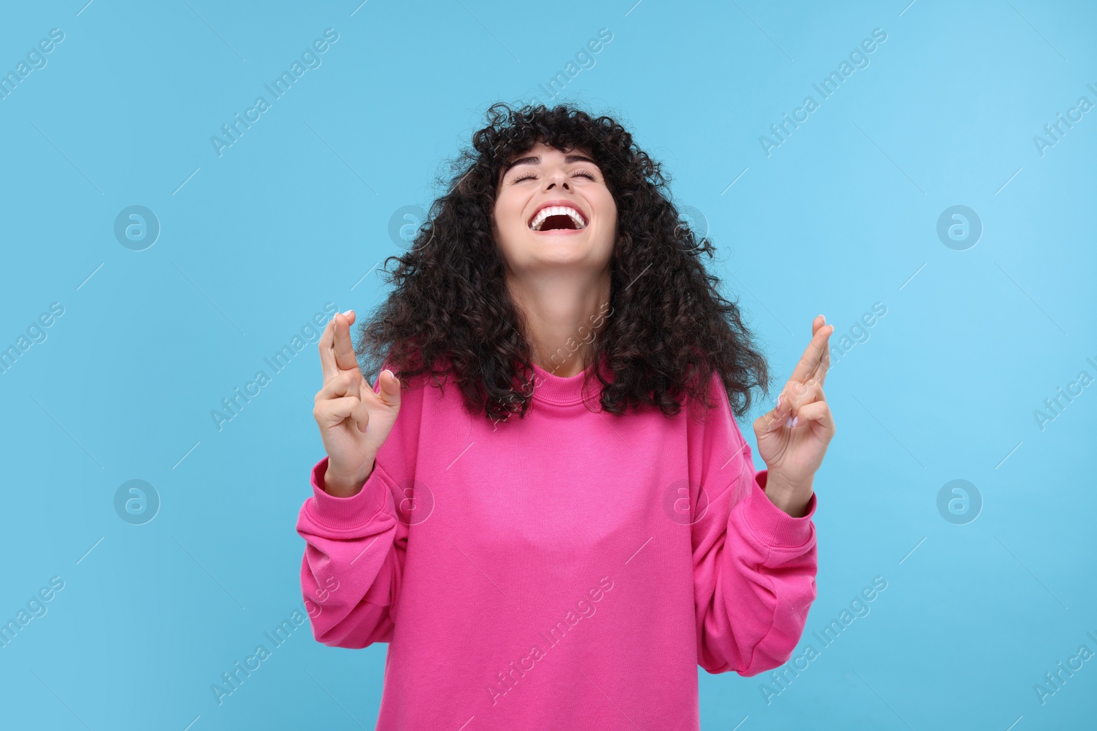 Photo of Woman crossing her fingers on light blue background