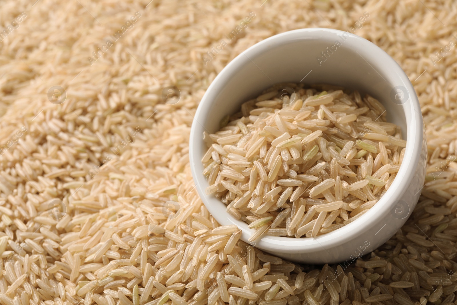 Photo of Ceramic bowl with raw brown rice on cereal