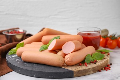 Photo of Delicious boiled sausages, basil and peppercorns on light table against white background, closeup