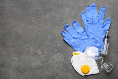 Photo of Flat lay composition with medical gloves, mask and hand sanitizer on grey background. Space for text