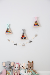 Wigwam shaped shelves, stuffed toys and garland indoors. Children's room interior design