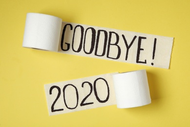Photo of Toilet paper with text Goodbye 2020 on yellow background, flat lay