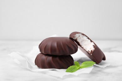 Photo of Delicious chocolate covered marshmallows with mint on white marble table