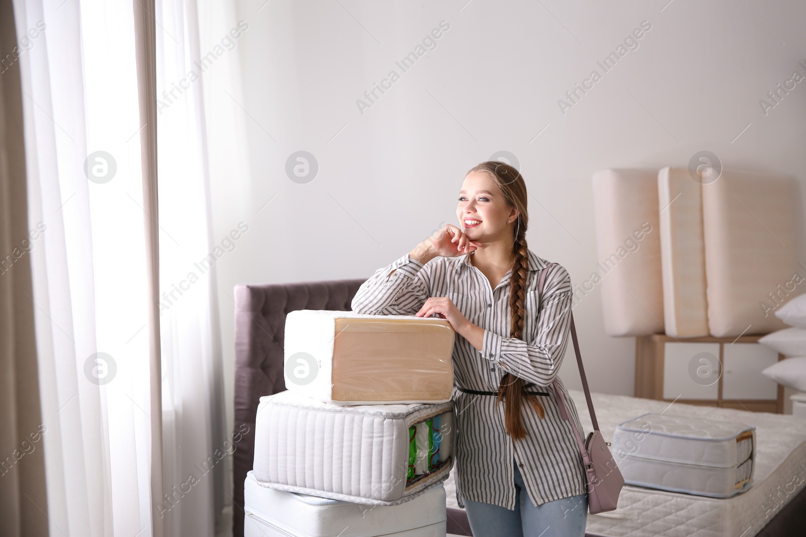 Photo of Young woman choosing mattress in furniture store