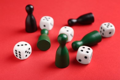 Many white dices and color game pieces on red background, closeup