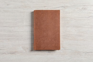 Hardcover book on white wooden table, top view