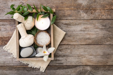 Photo of Box with spa cosmetics, accessories and orchid on wooden background