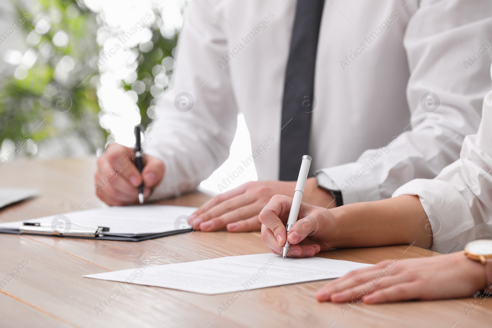 Photo of Woman signing contract at table in office, closeup.