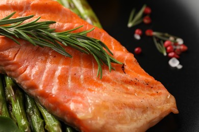 Tasty grilled salmon with asparagus and rosemary on plate, closeup