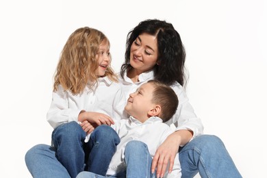 Little children with their mother sitting together on white background