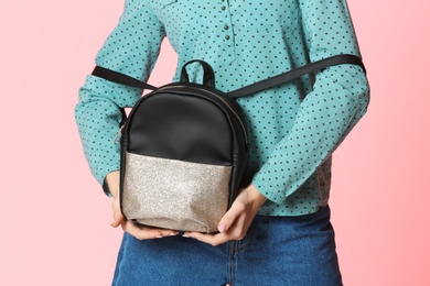 Fashionable woman with backpack on color background, closeup