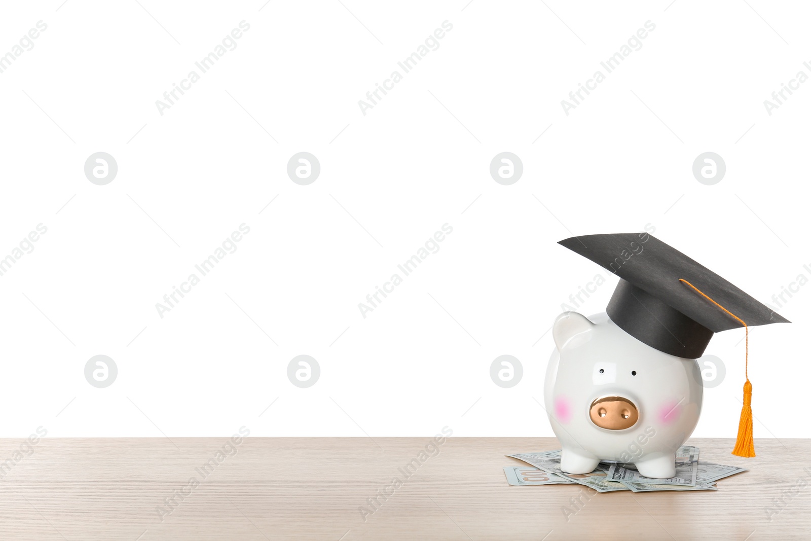 Photo of Piggy bank with graduation hat and money on table against white background