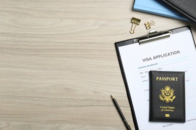 Photo of Visa application form, passport and stationery on wooden table, flat lay. Space for text