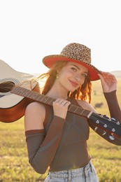 Beautiful happy hippie woman with guitar in field