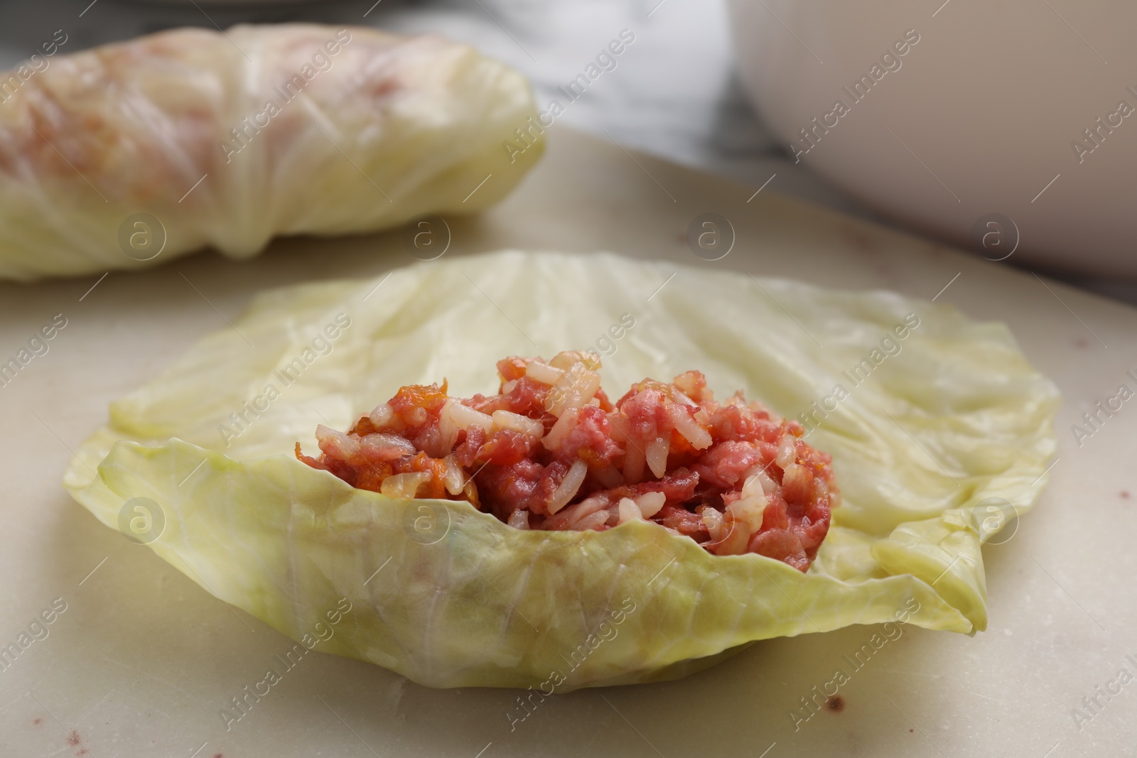 Photo of Preparing stuffed cabbage roll on board, closeup