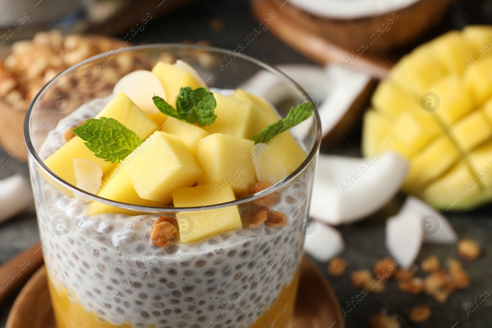 Photo of Delicious chia pudding with mango, mint and granola in glass, closeup