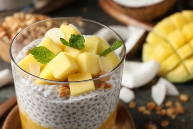 Delicious chia pudding with mango, mint and granola in glass, closeup